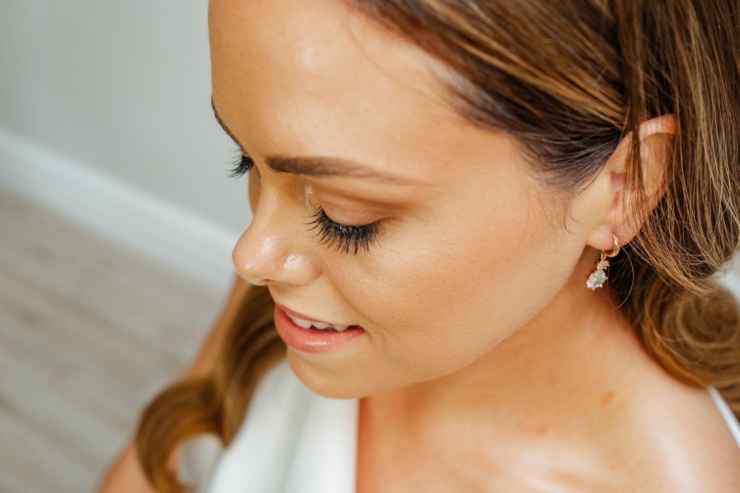 Close up beauty shot showing delicate bridal earrings and natural makeup.