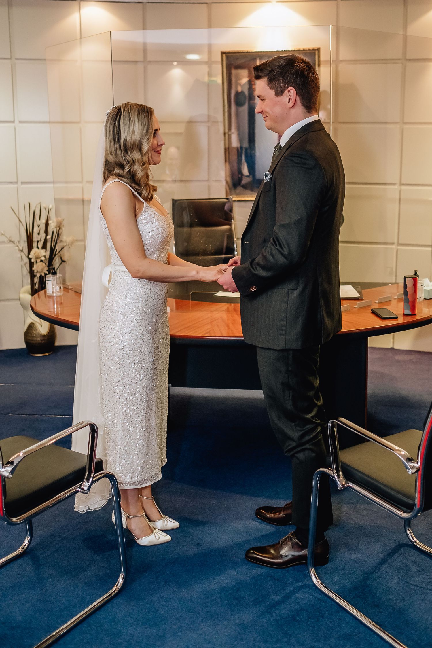 A couple in formal attire standing together in an elegant office or meeting space.