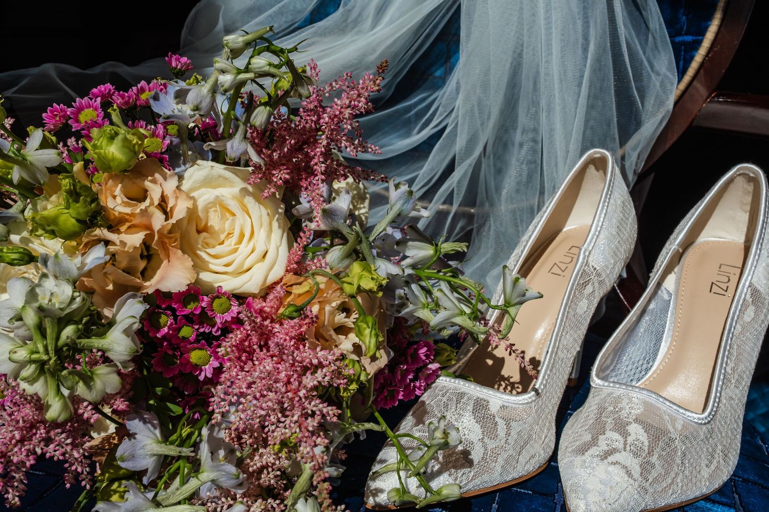 Bridal accessories including delicate shoes and floral arrangements in pink and blue tones.