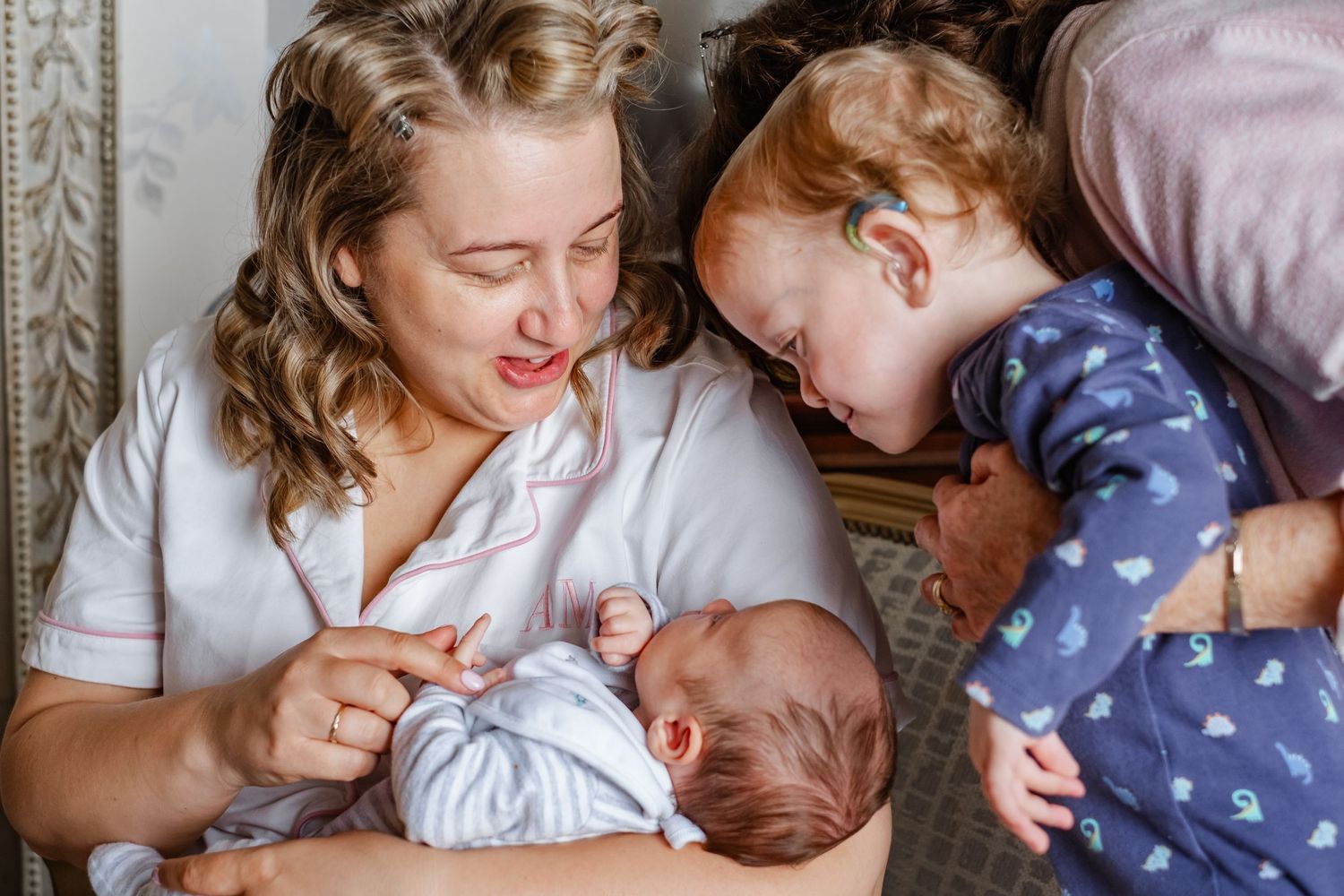 A tender family moment with a newborn baby and toddler sharing affection.