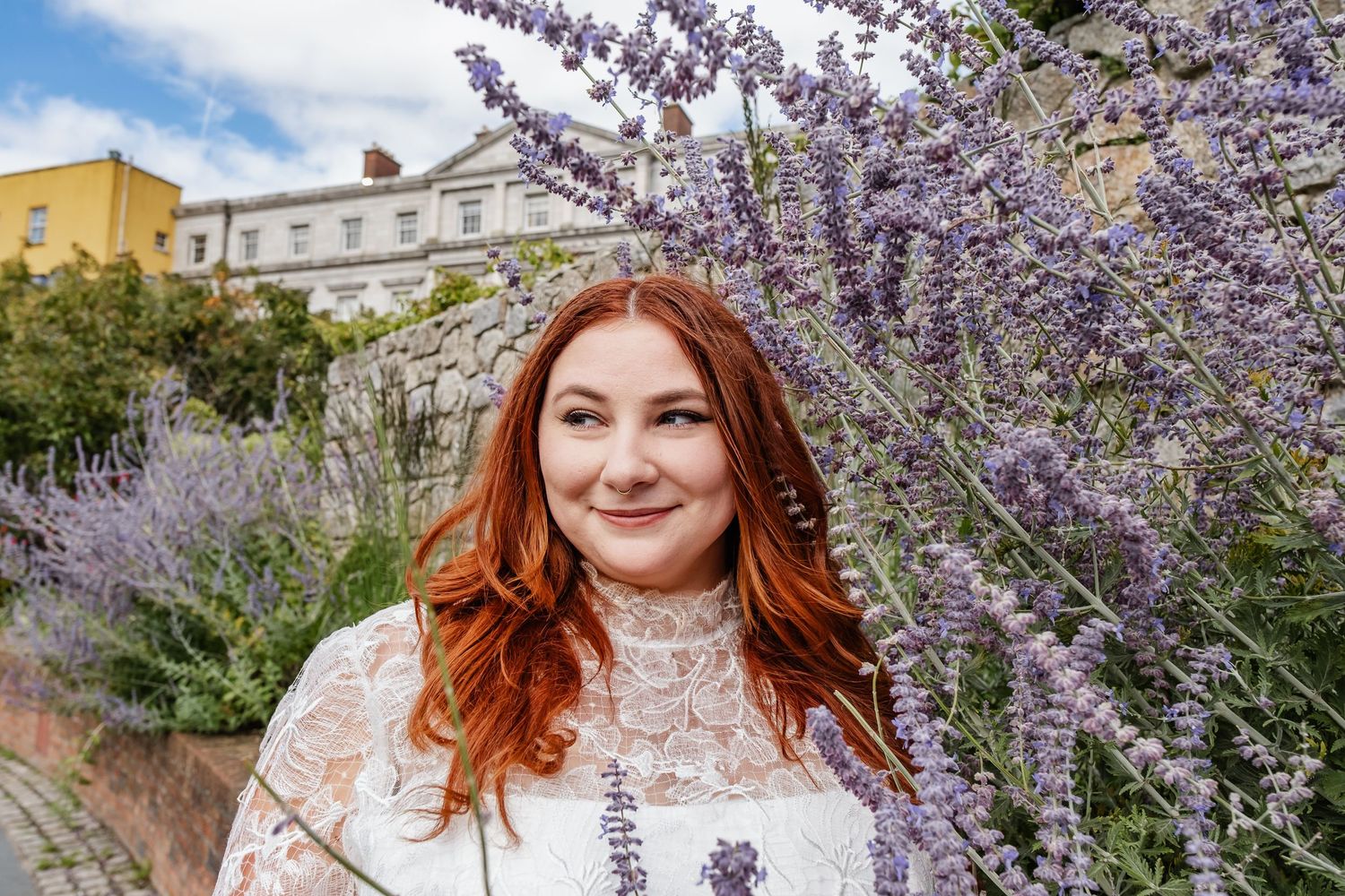 A portrait amidst blooming purple wisteria flowers against a bright blue sky.