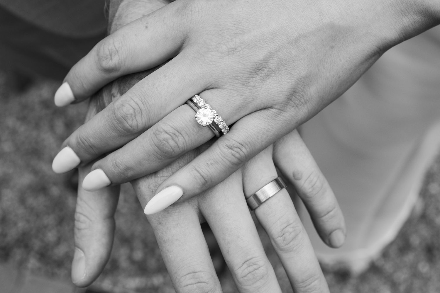 Close-up black and white photo of wedding rings and hands showing new marriage bands.