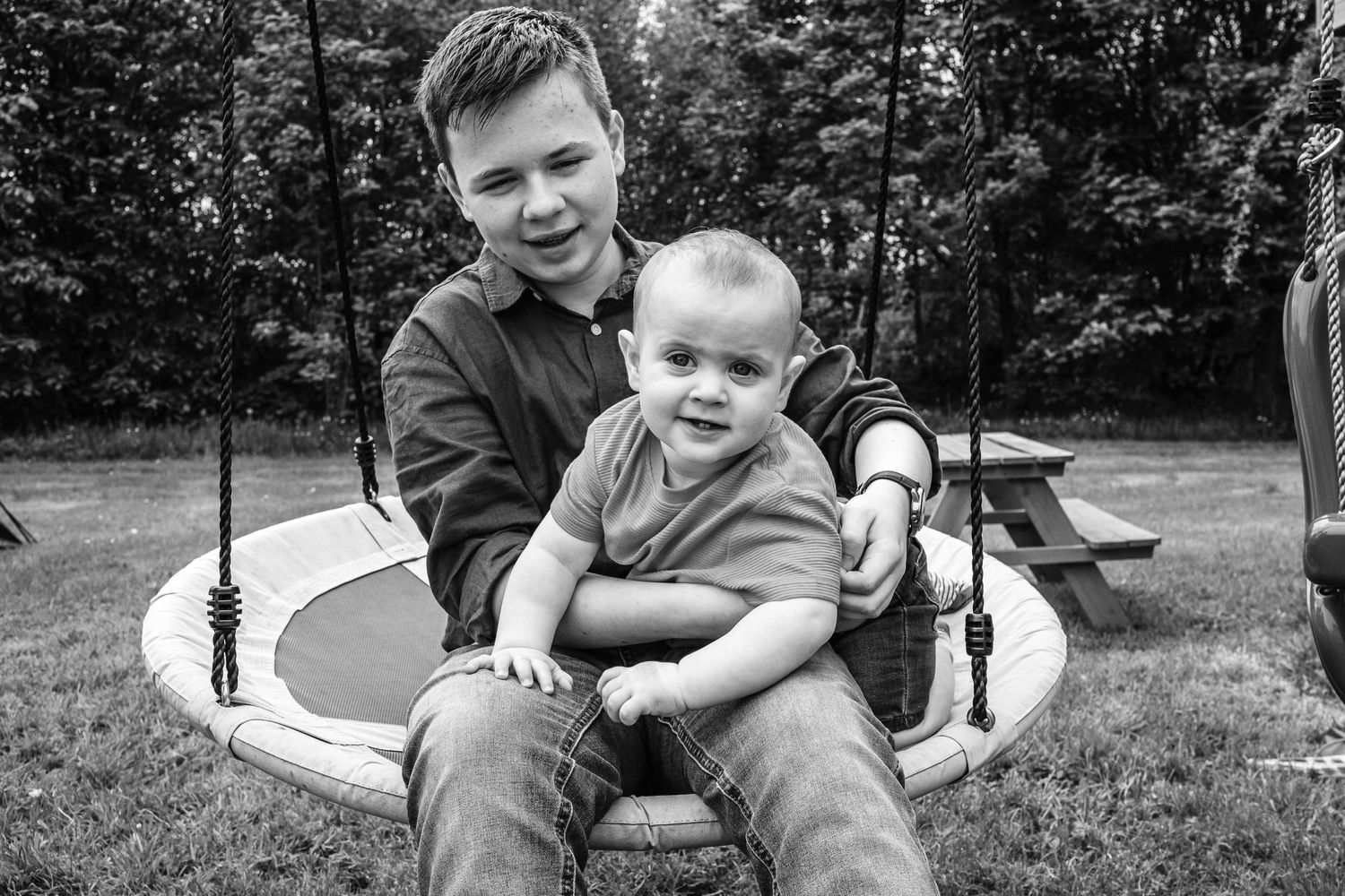 Black and white capture of tender moment on a swing set.