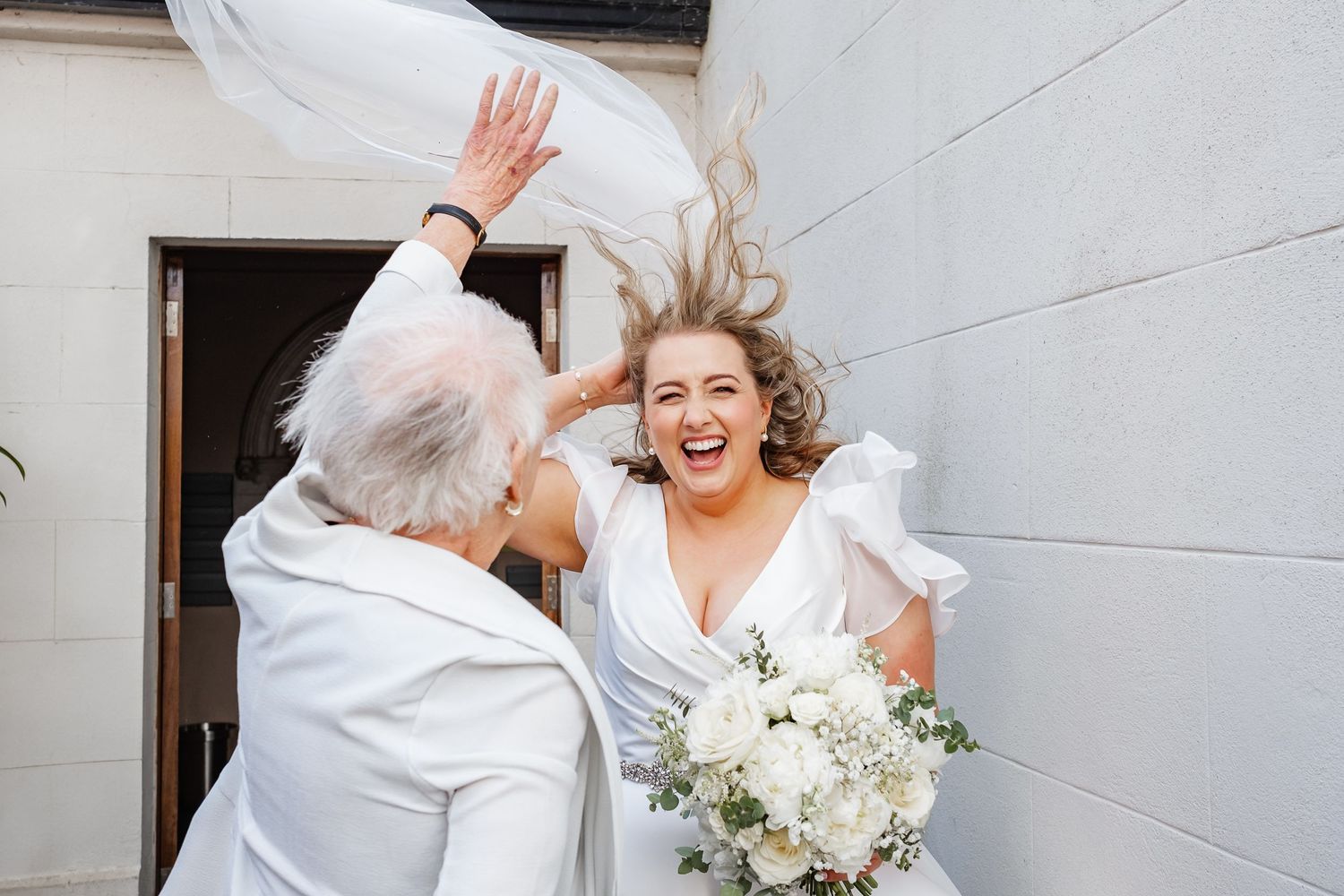 Joyful celebration moment shared between wedding guests outside a church entrance.