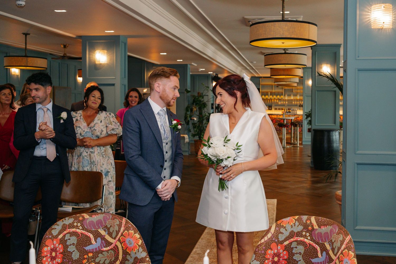 Wedding reception scene in an elegant venue with blue walls and pendant lighting.