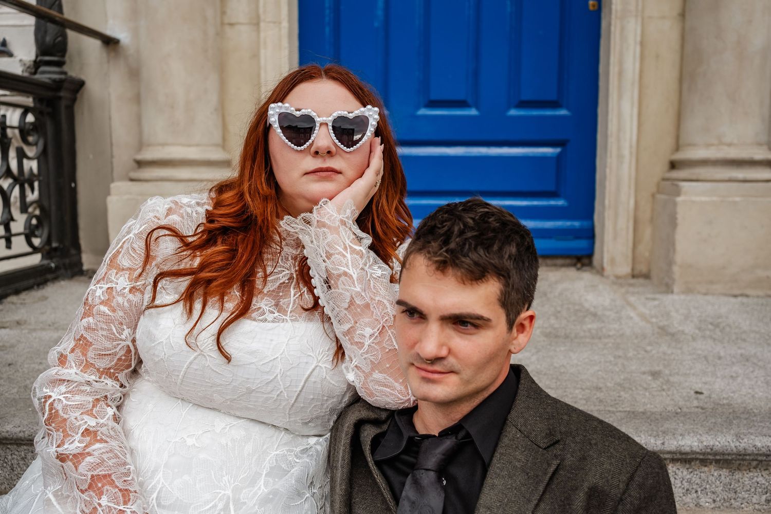 A couple poses outside a building with a bright blue door.