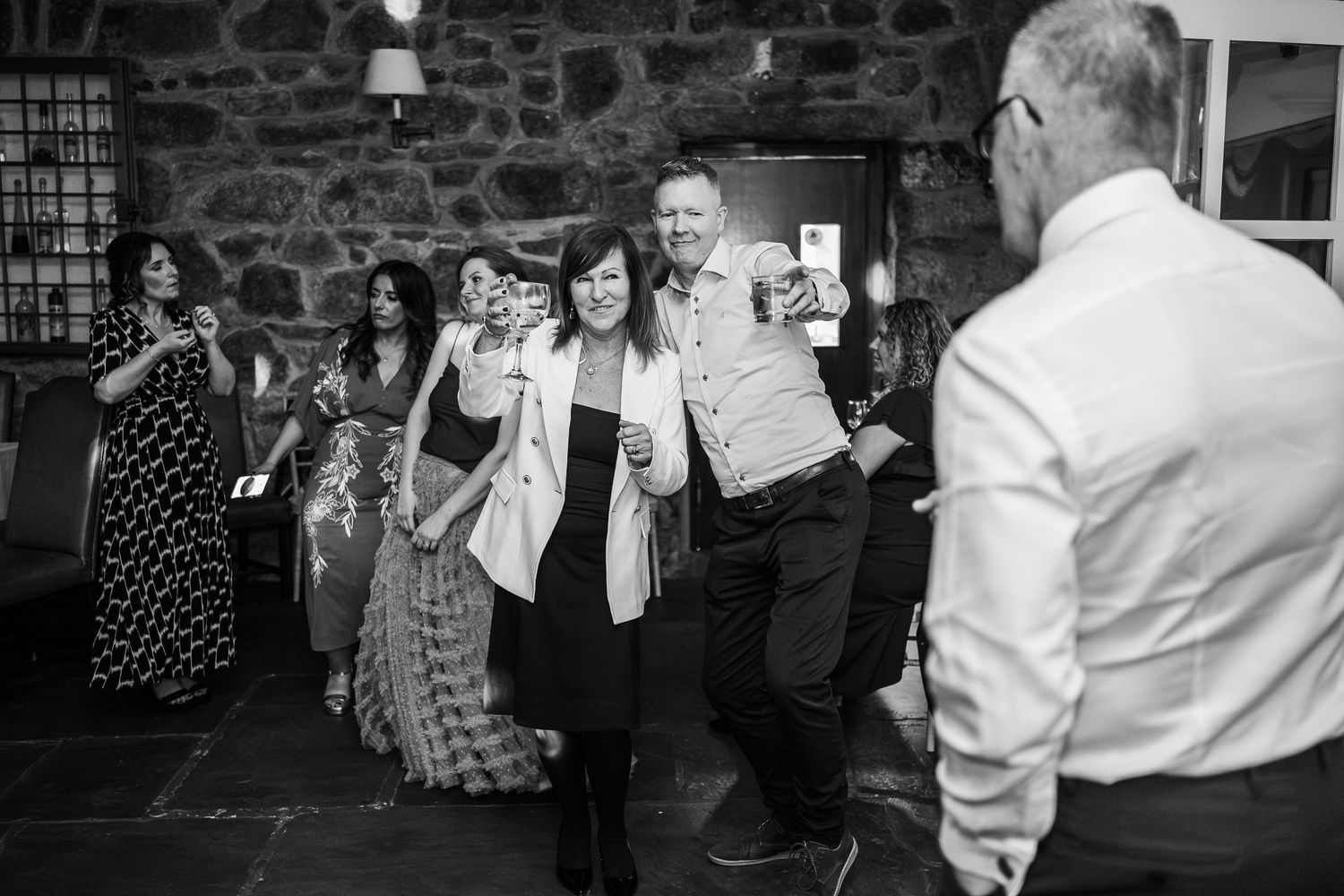 Wedding guests dancing and celebrating together in rustic stone venue.