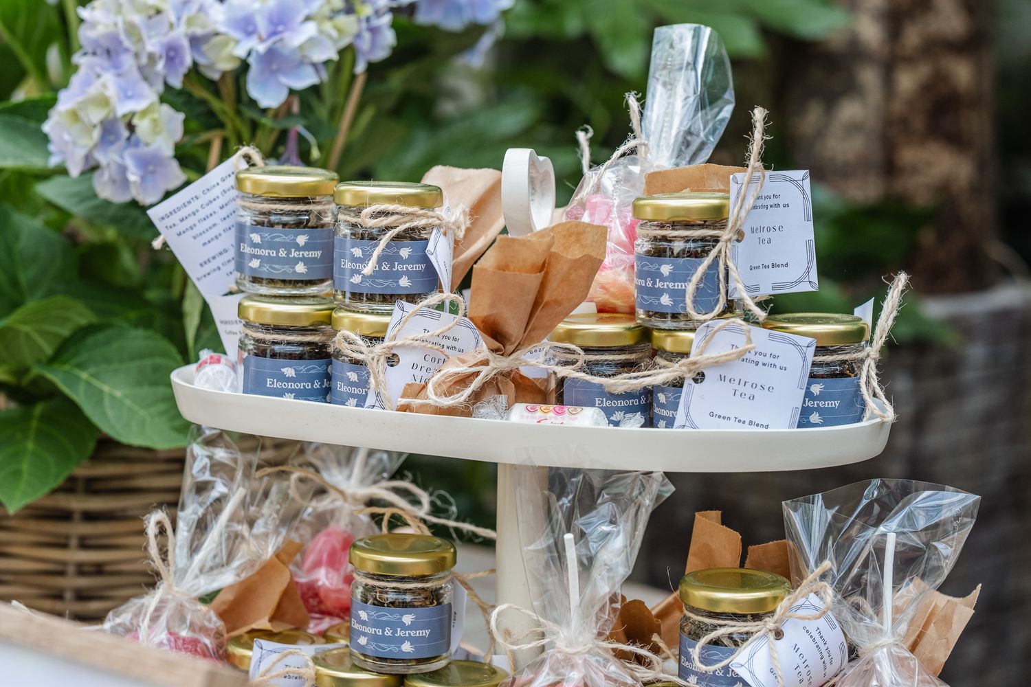 Elegant tiered display of artisan jam jars with gold lids and twine bows, surrounded by hydrangea blooms.