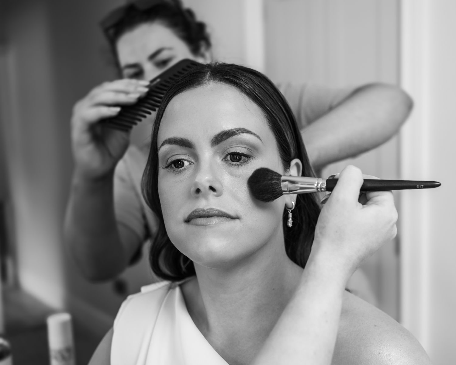 Behind the scenes photo of bridal makeup application in black and white.