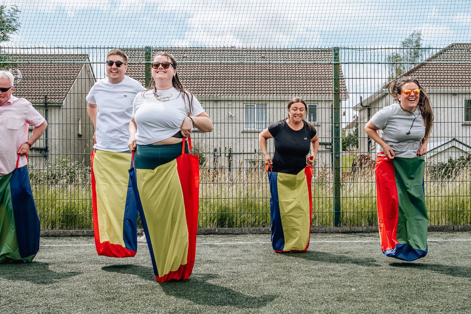 Group participating in outdoor sack race activity wearing colorful potato sacks.