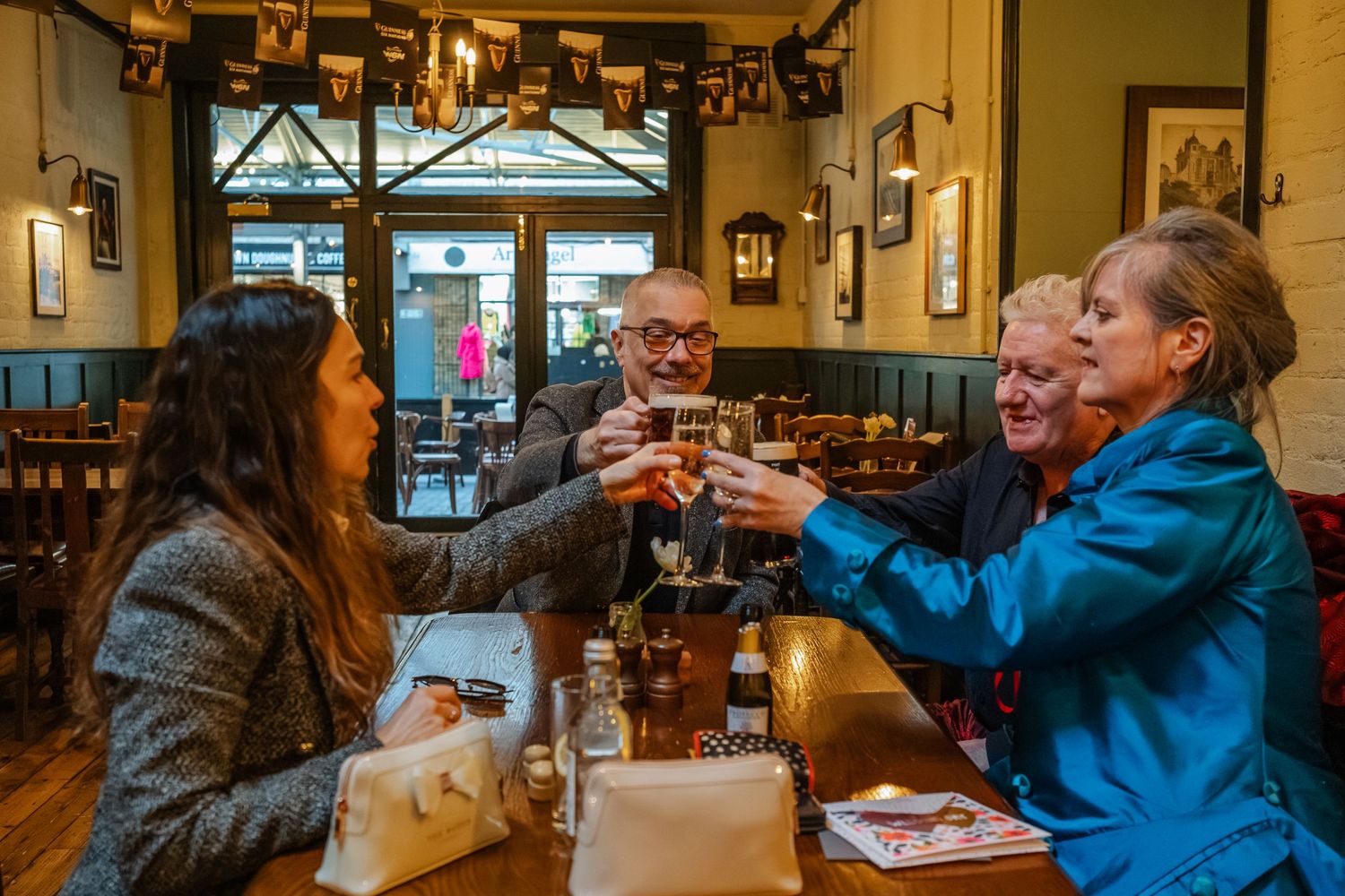 Friends toasting drinks together at a cozy pub table.