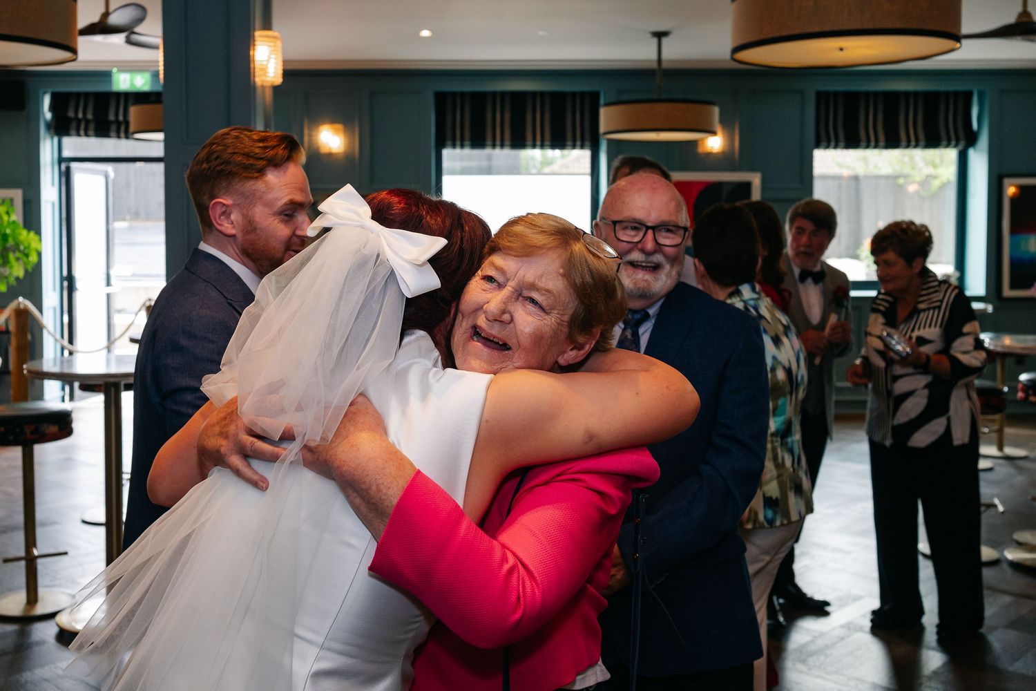 Heartfelt embraces and celebrations during a wedding reception in an industrial-chic venue.