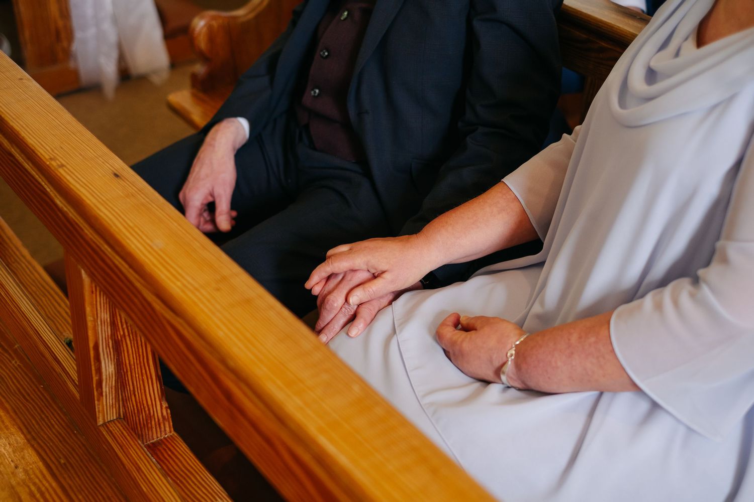 Close-up shot of hands signing wedding documents at a wooden table during marriage ceremony.