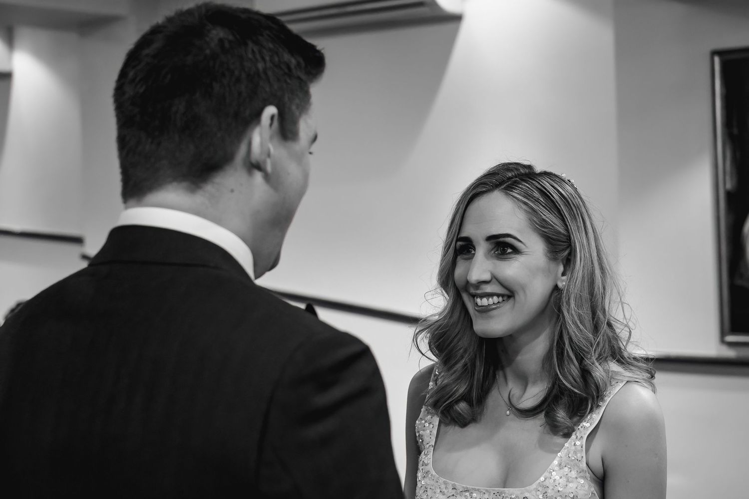 An intimate black and white portrait capturing a joyful wedding moment indoors.