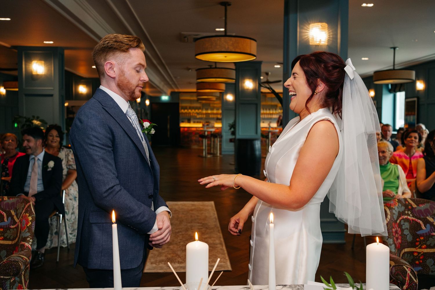A couple shares a joyful moment during their wedding ceremony in a restaurant setting.