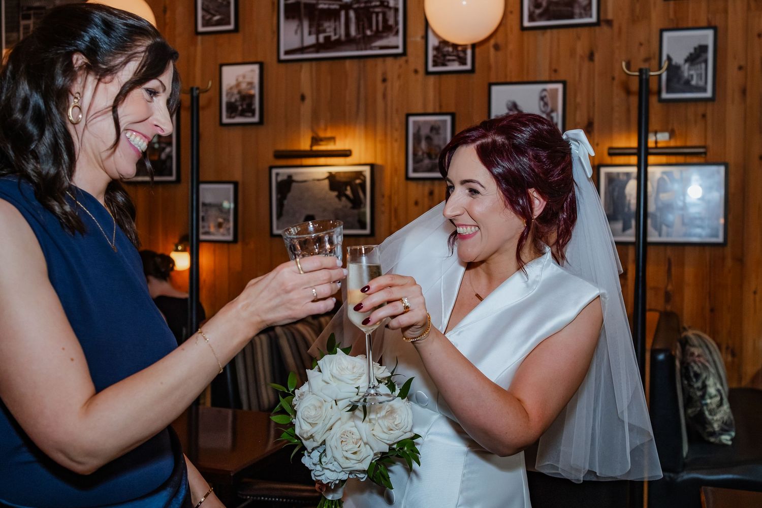 Wedding celebration in wood-paneled room with vintage photos on walls.