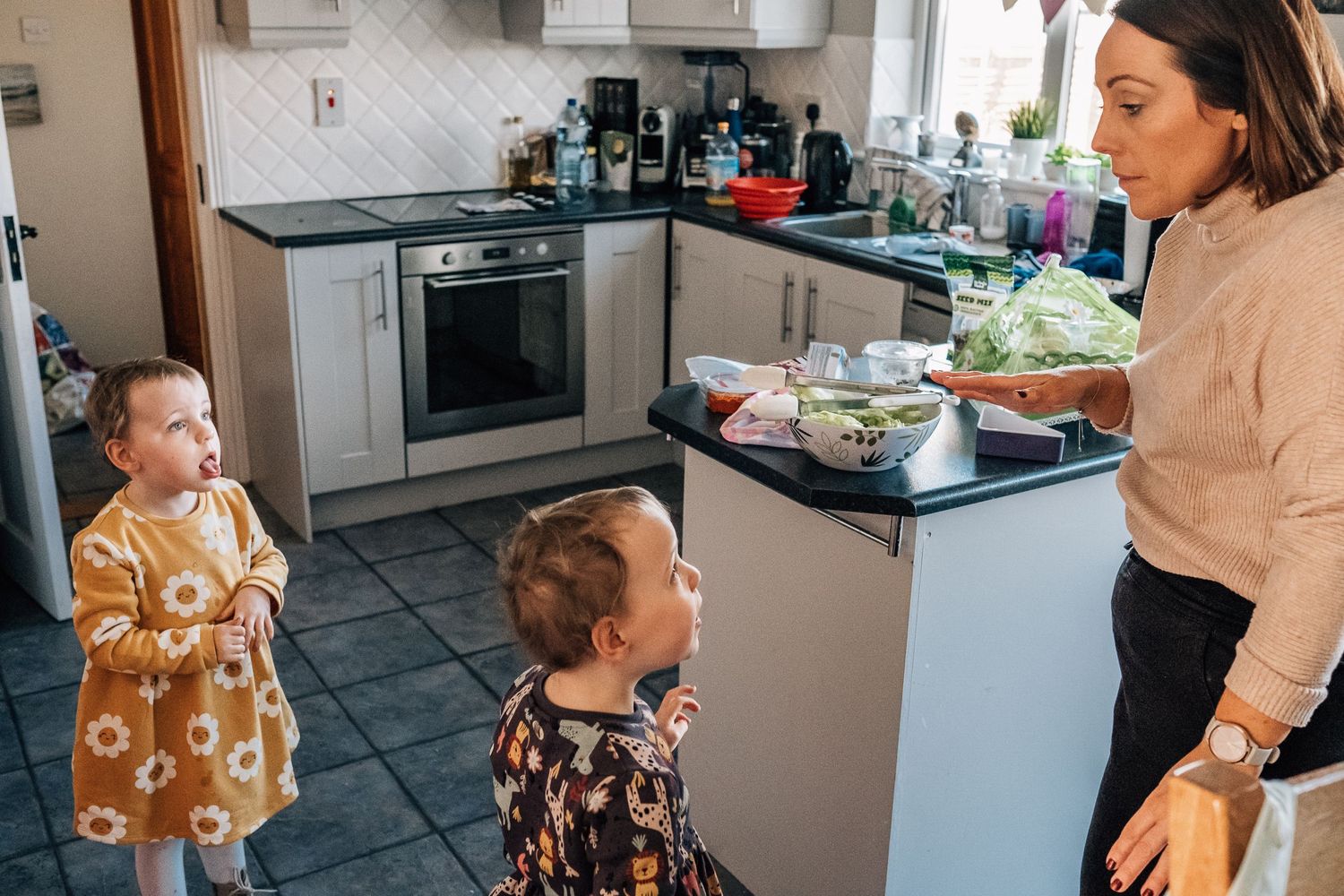 Modern kitchen scene with people interacting near countertops and appliances.