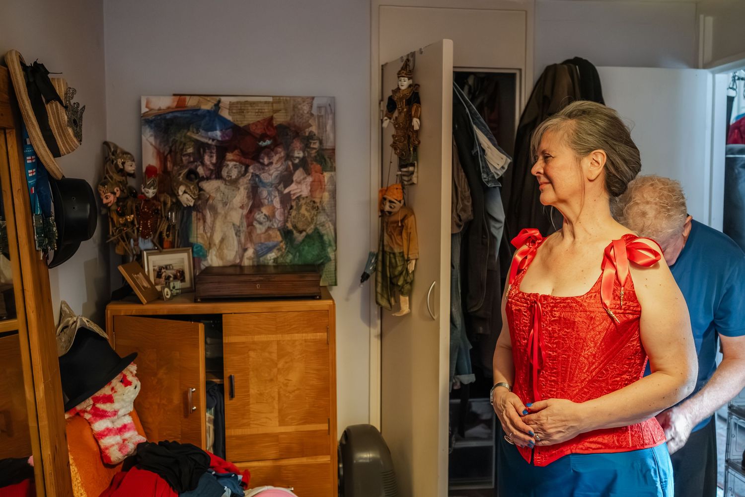 A red dress being fitted in a room with photos and decorations on display.