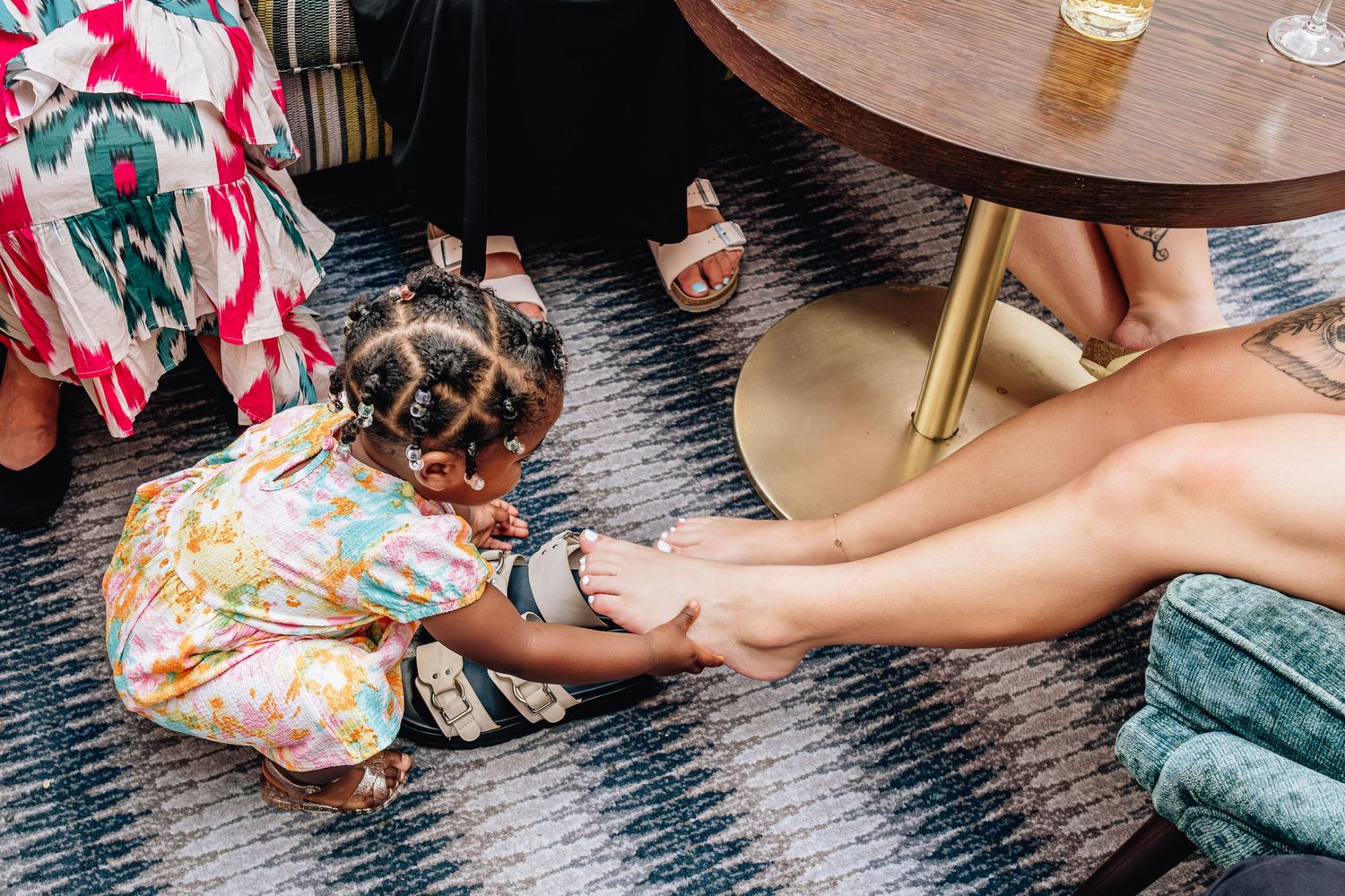 Top-down view of legs and feet on a patterned rug next to a wooden table.
