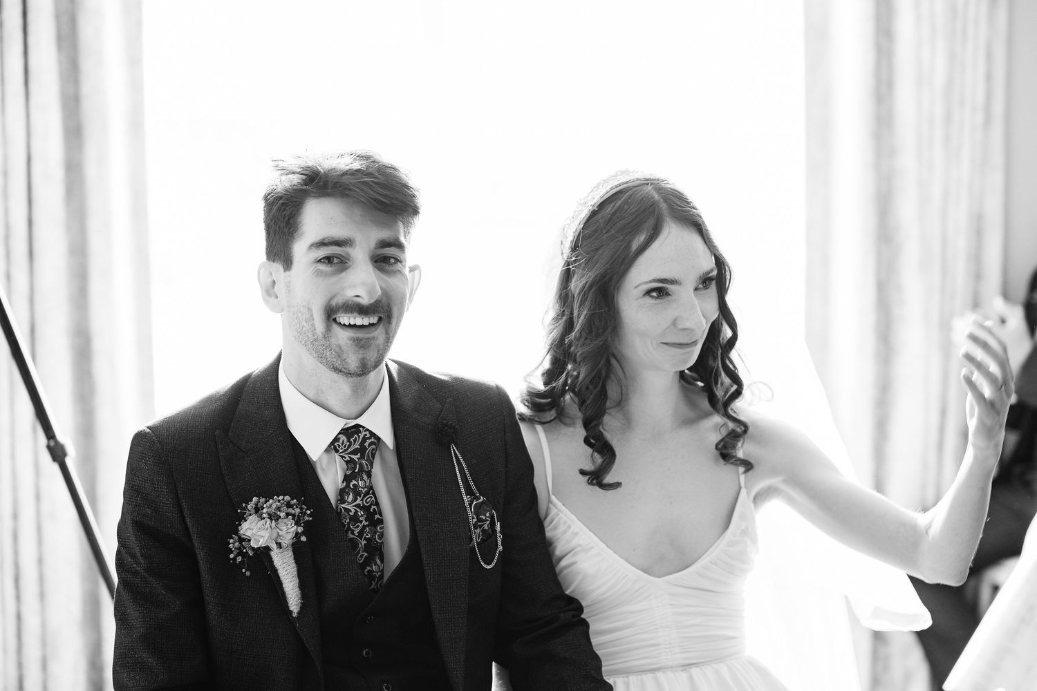 Wedding party laughs together in a candid black and white photo during celebration.