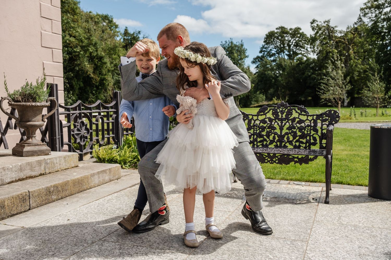Three people sharing a playful moment on stone steps outside a elegant building.