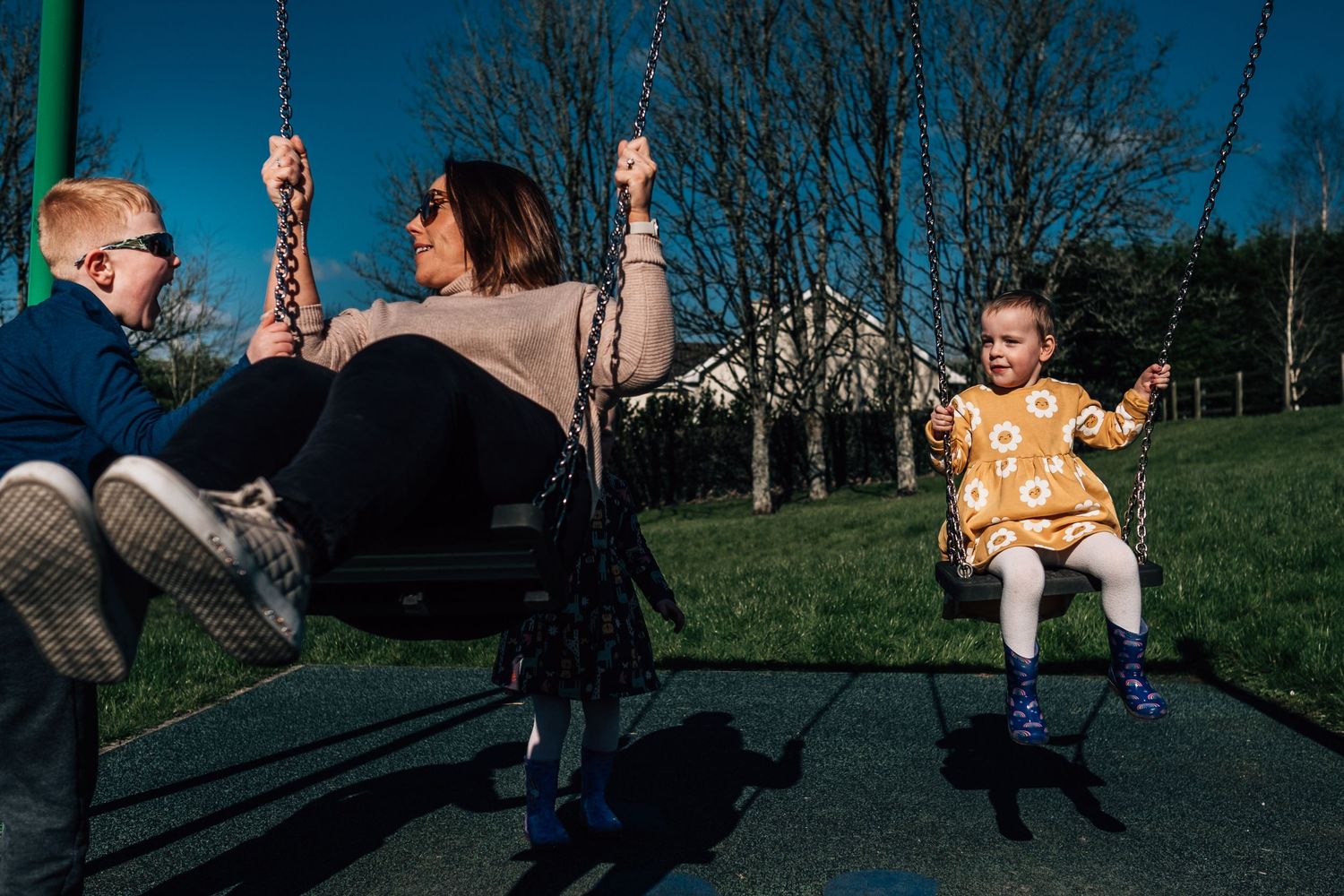 A playful scene at a park with people enjoying swings on a sunny afternoon.