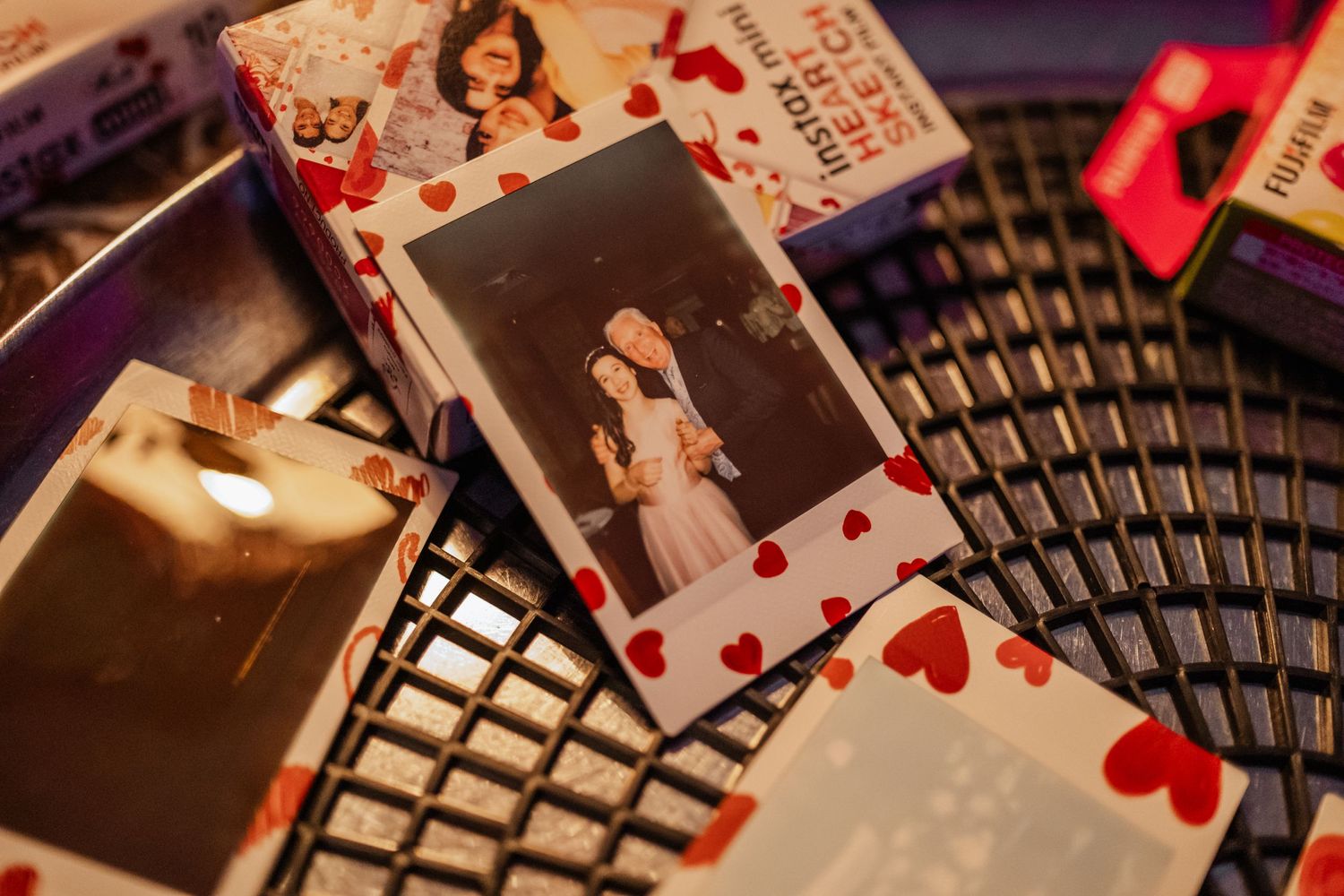Vintage-style polaroid photos with heart decorations scattered on a dark surface.