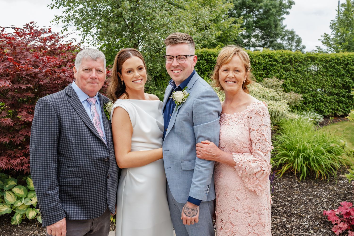 Formal outdoor family portrait in front of landscaped garden with red maple tree.