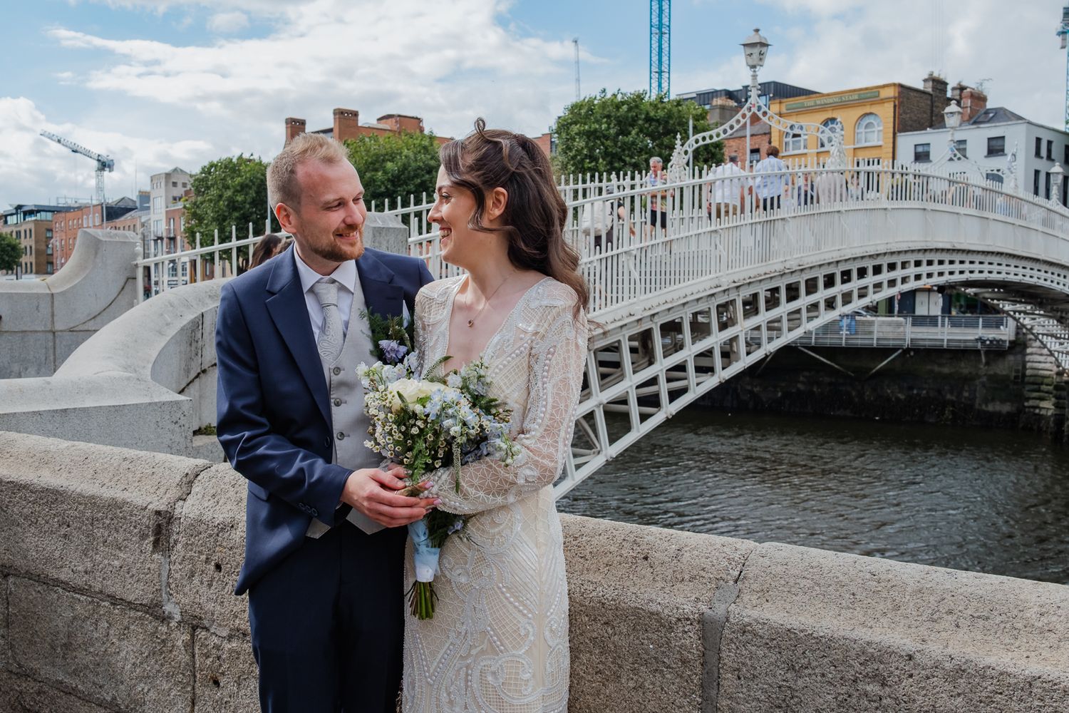 A couple shares a romantic moment on the iconic Ha'penny Bridge in Dublin, Ireland during their wedding photoshoot.