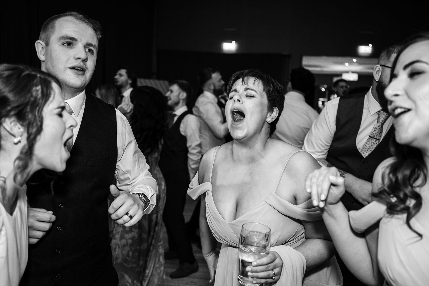 Wedding guests dance and celebrate together in a lively black and white party scene.