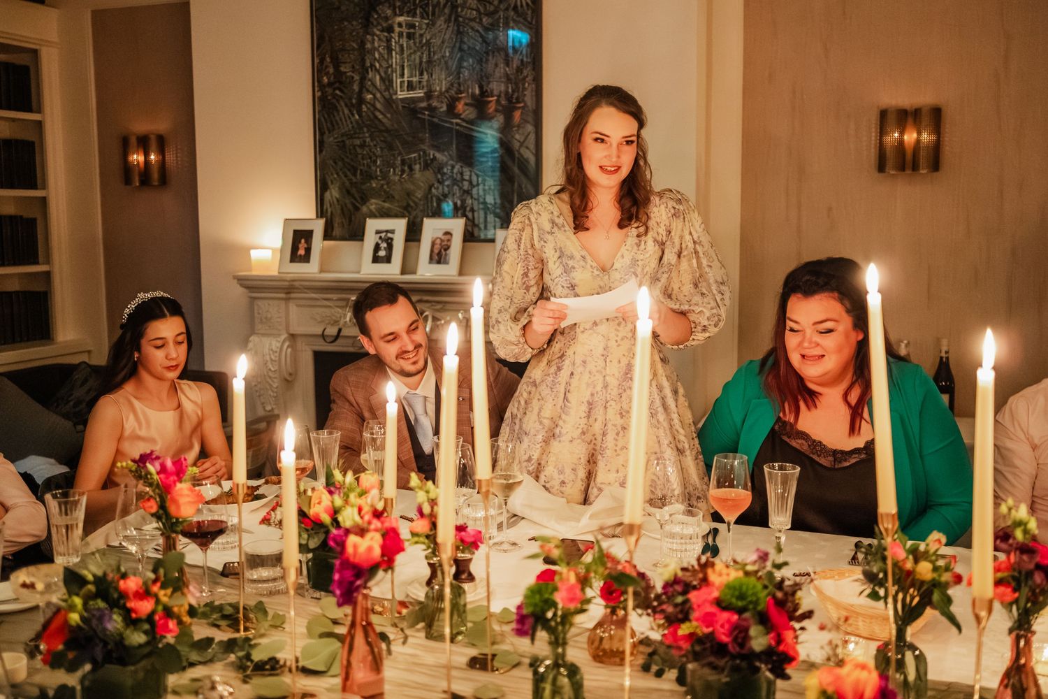 A candlelit wedding reception dinner features elegant table settings with pink floral centerpieces.