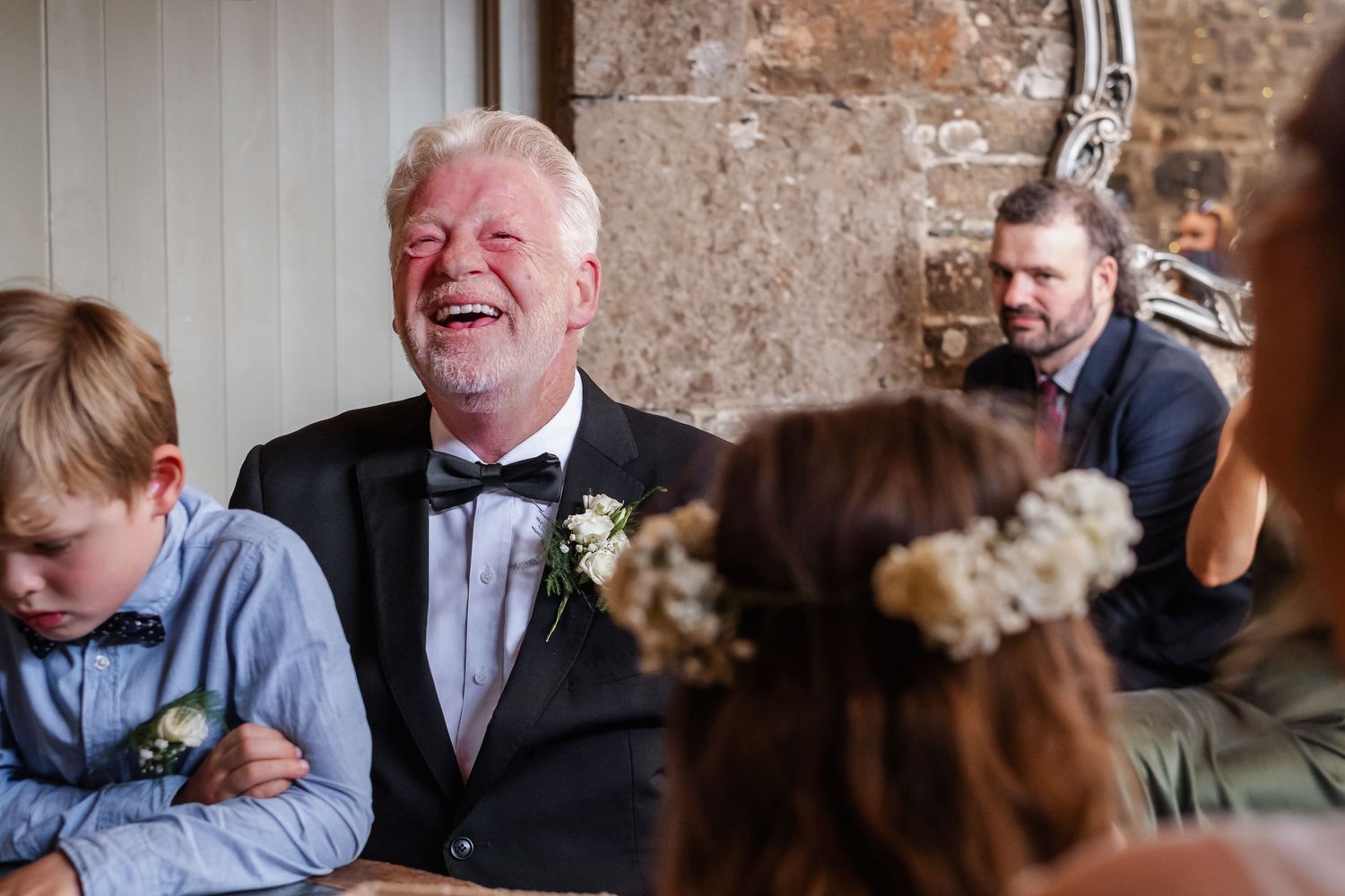 A candid moment of laughter during a formal event in a rustic stone interior.
