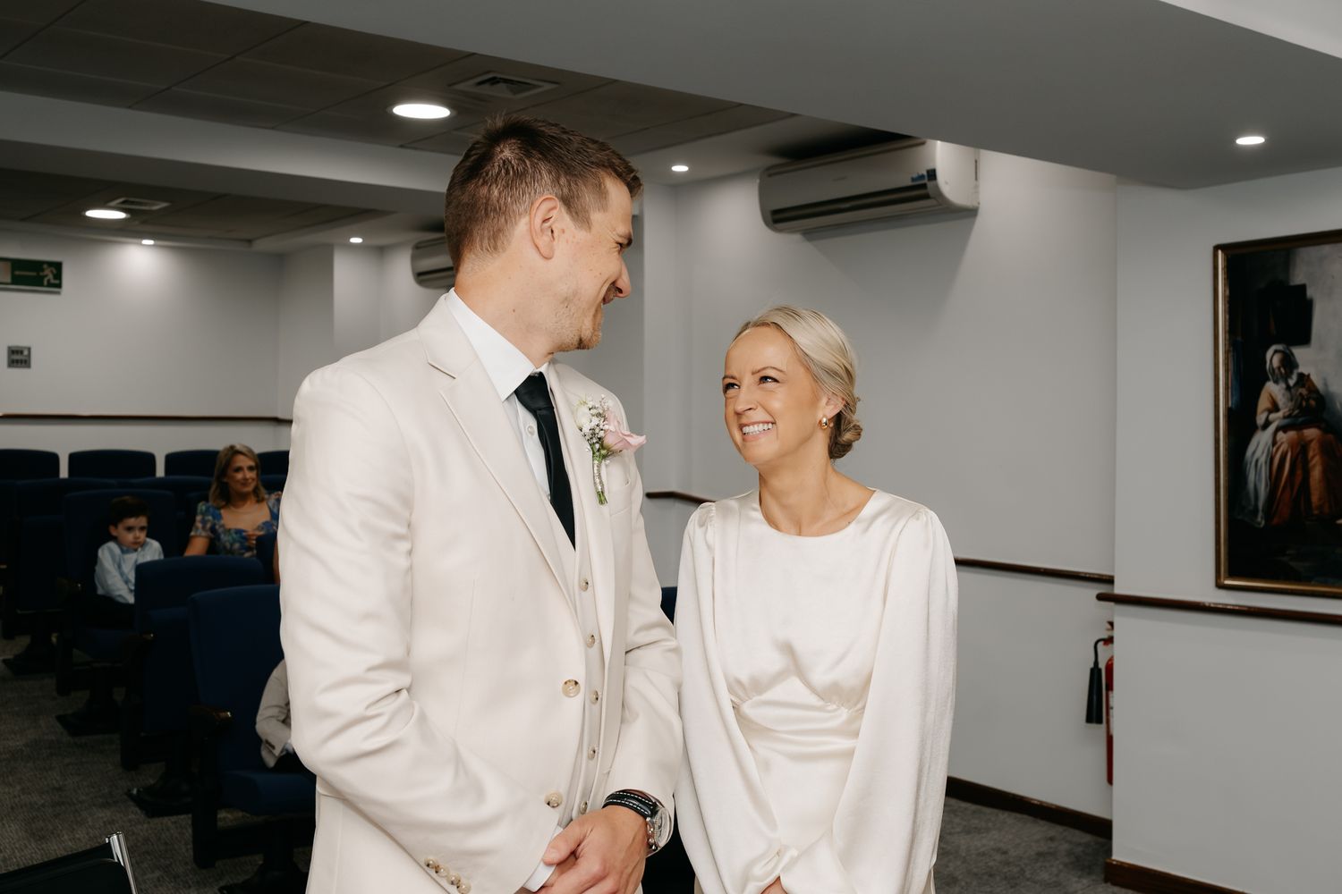 Bride and groom exchange smiles during intimate civil wedding ceremony in a modern venue.