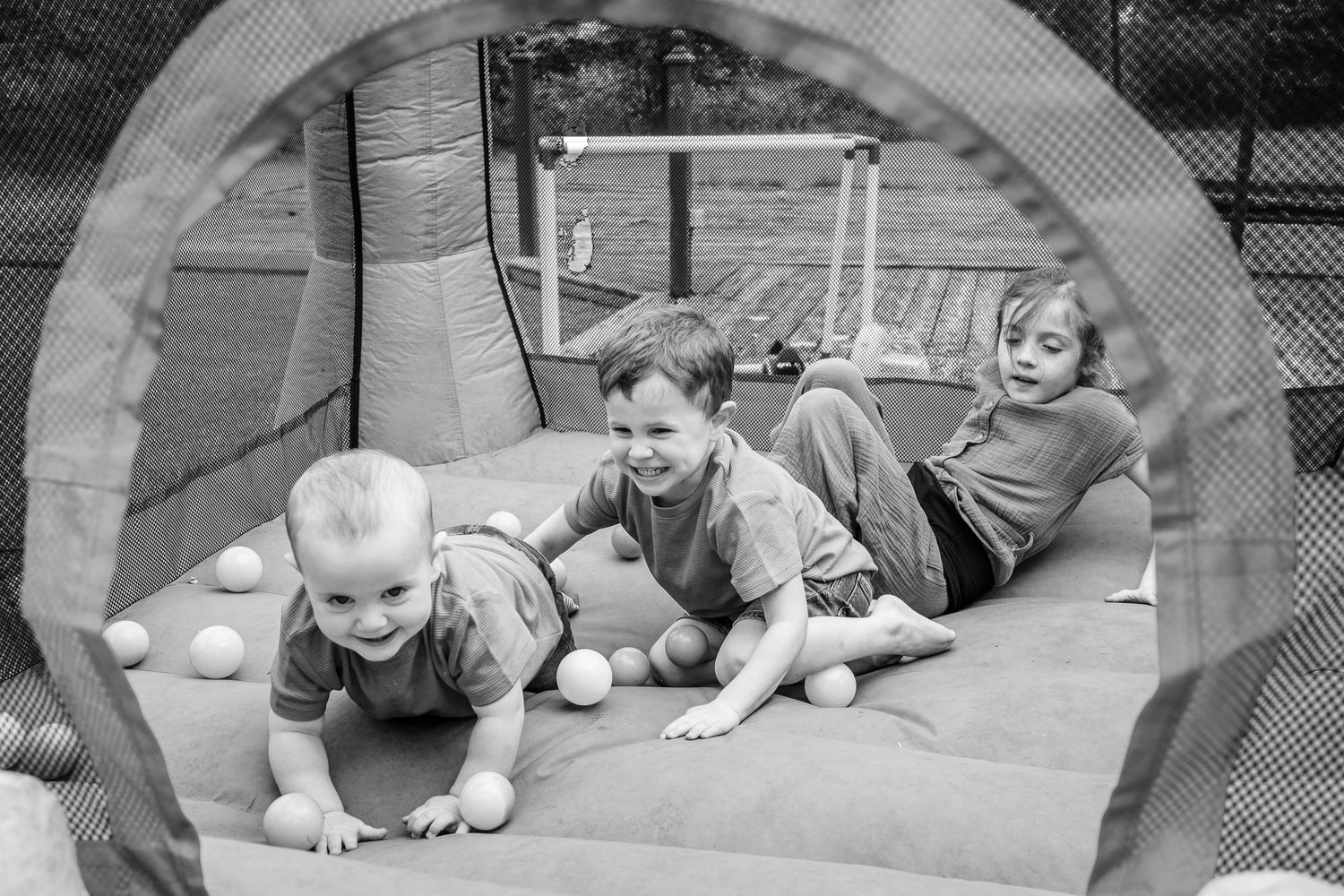 Inside view of a play tunnel with three individuals lying down and playing together.