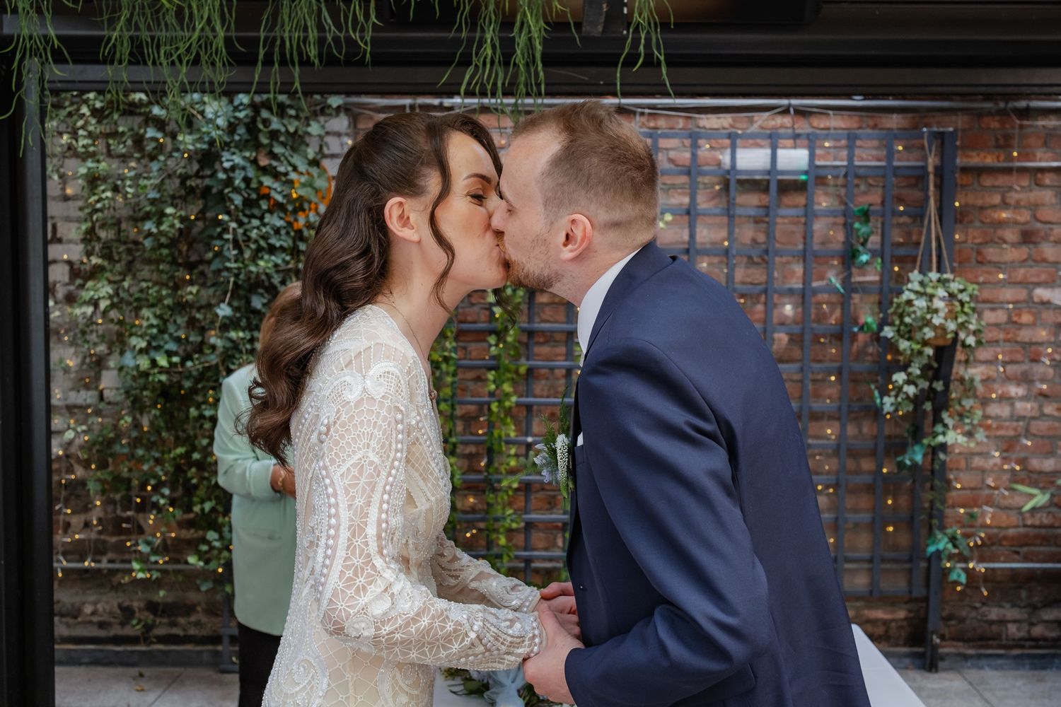 Couple sharing their first dance at a modern urban venue with exposed brick and greenery decor.