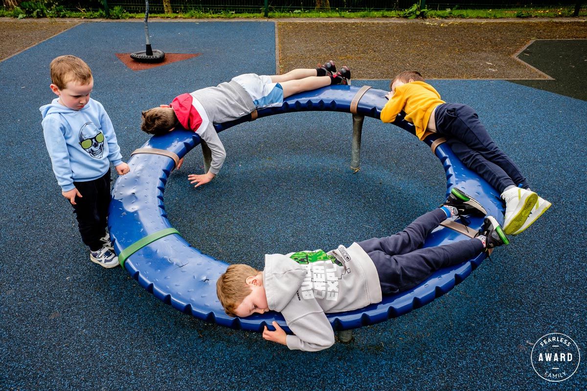 A sequence of photos shows a child rolling sideways down a small slope on a playground surface.