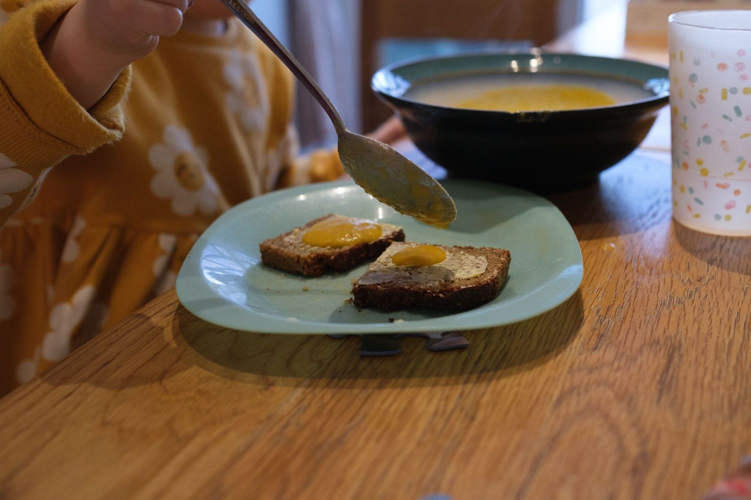 Toast on green plate with drink cup visible on wooden table.