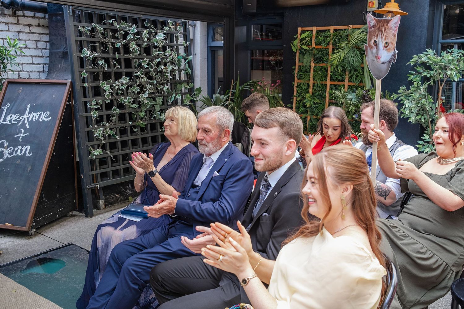 Wedding guests celebrate during an outdoor reception at a countryside venue.