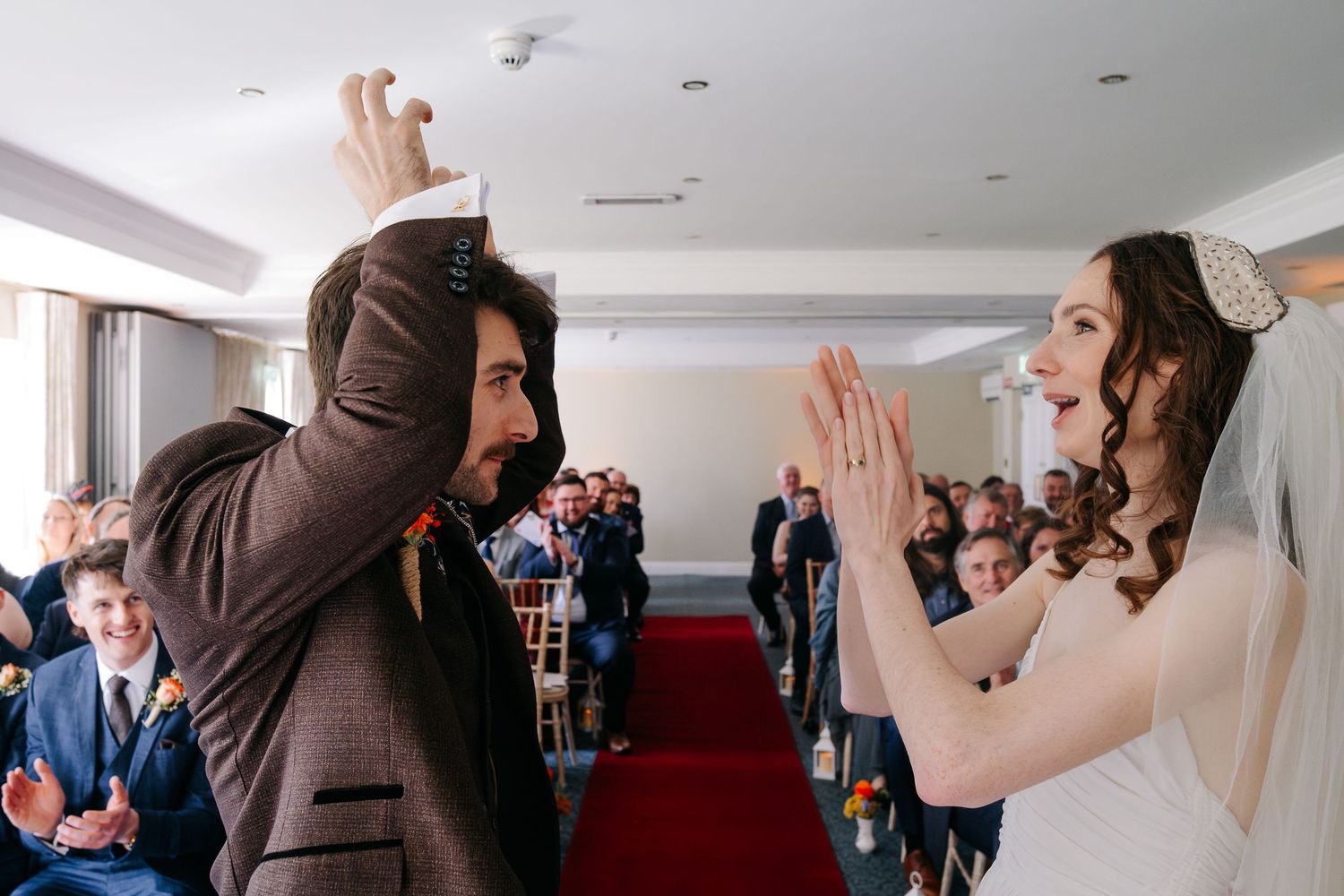 Wedding guests dance and celebrate with raised hands during a joyous reception celebration.