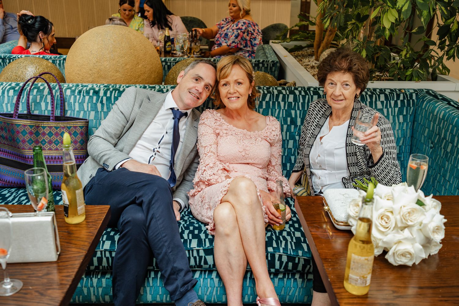 Wedding celebration on turquoise vintage sofa with festive drinks.