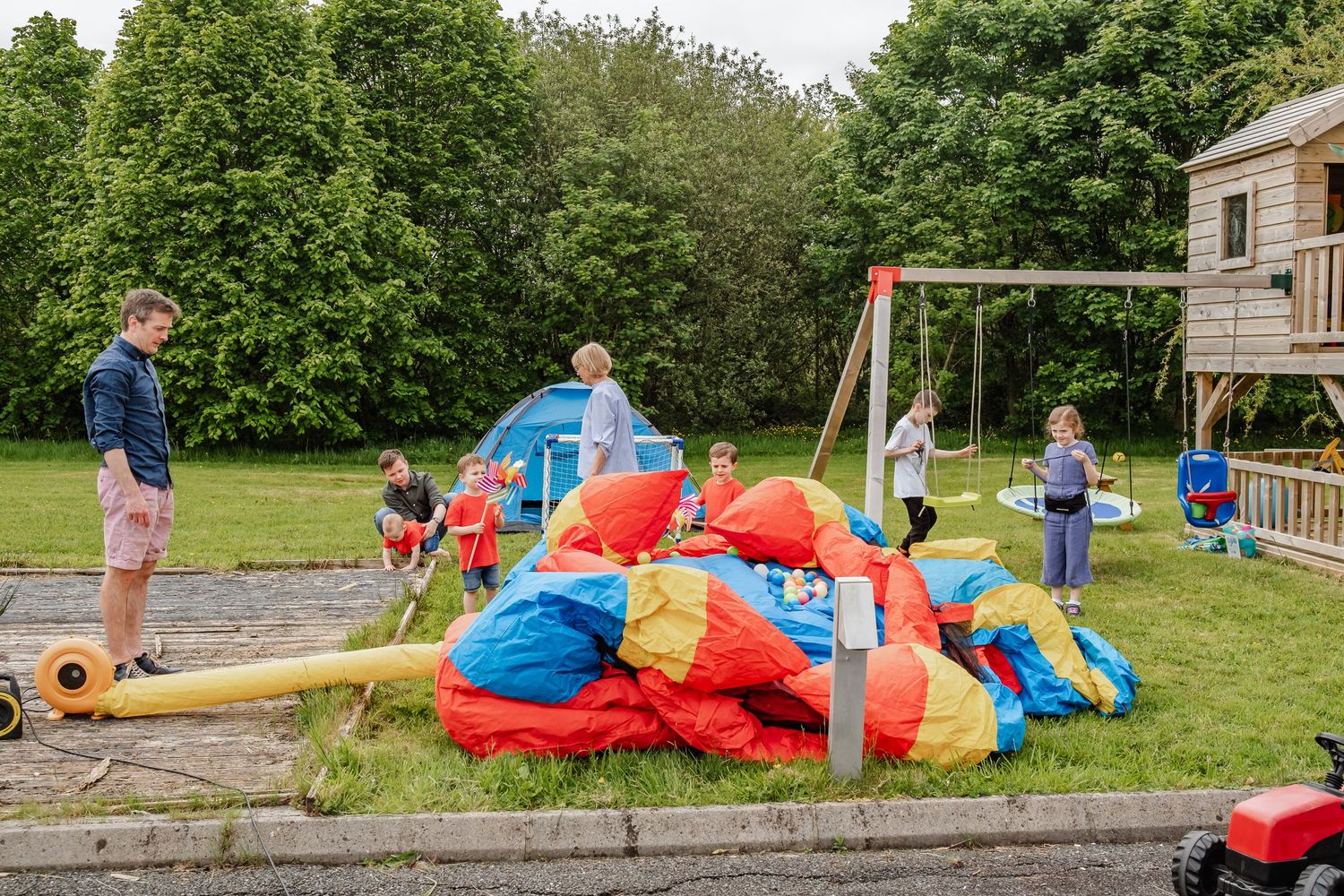 Children playing on colorful inflatable bouncy equipment in backyard garden.