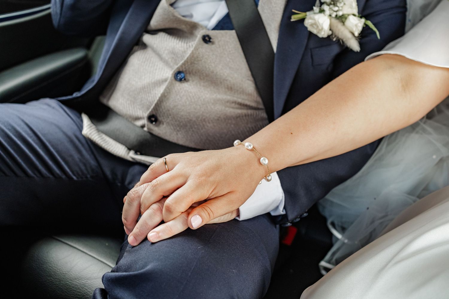 Close-up of joined hands showing wedding rings in car interior.