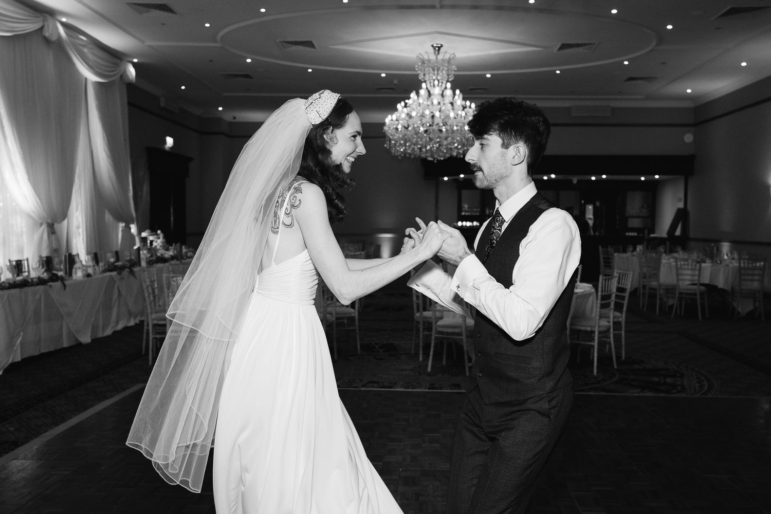 Romantic first dance in a grand ballroom with dramatic lighting and chandelier.