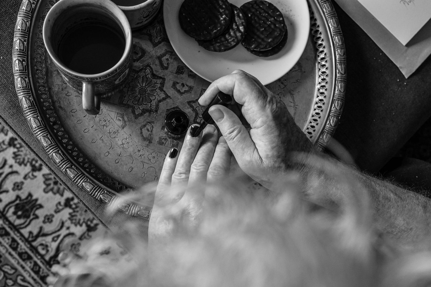 Black and white overhead view of coffee cup and blackberries on decorative tray.