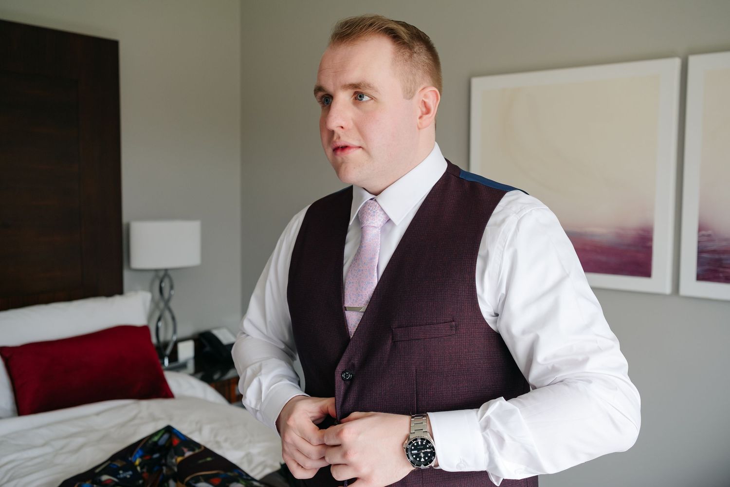 Groomsmen getting ready in a hotel room wearing formal attire.