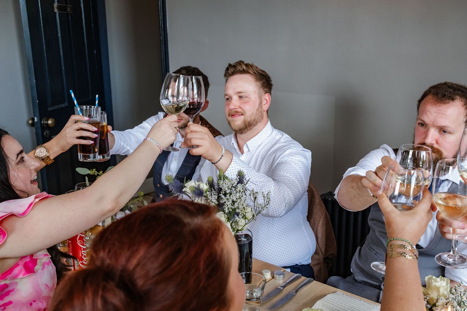 Wedding guests raise glasses in a toast during reception celebration.