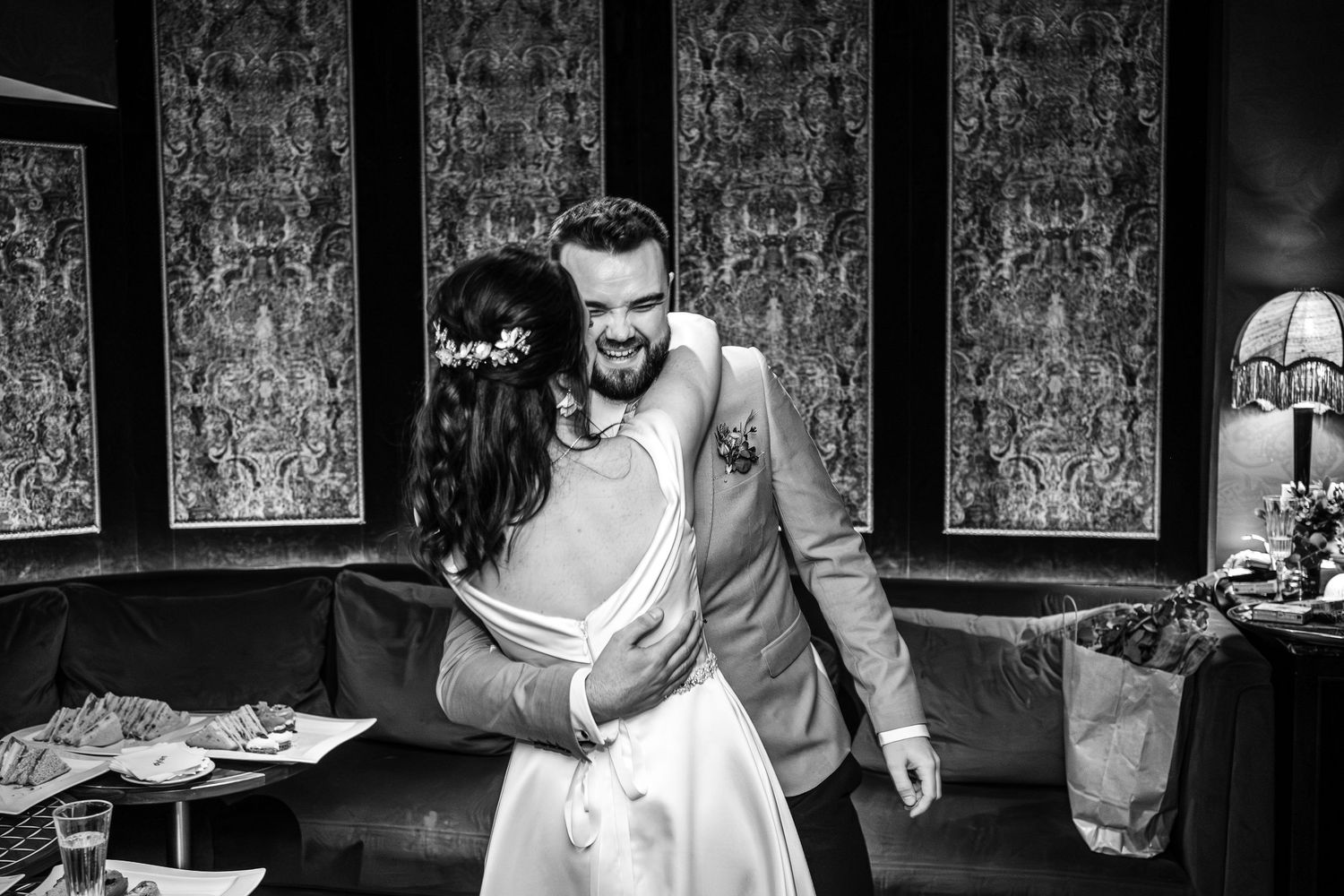 Artistic black and white wedding photos in venue with patterned wallpaper.