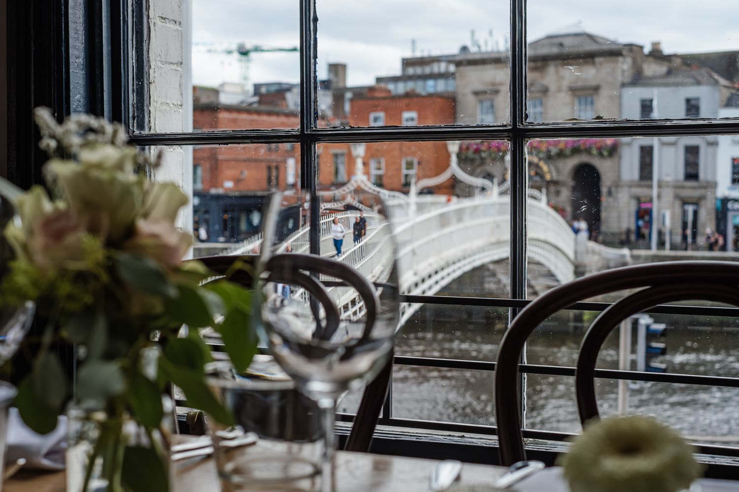 Modern restaurant interior with large windows overlooking city buildings.