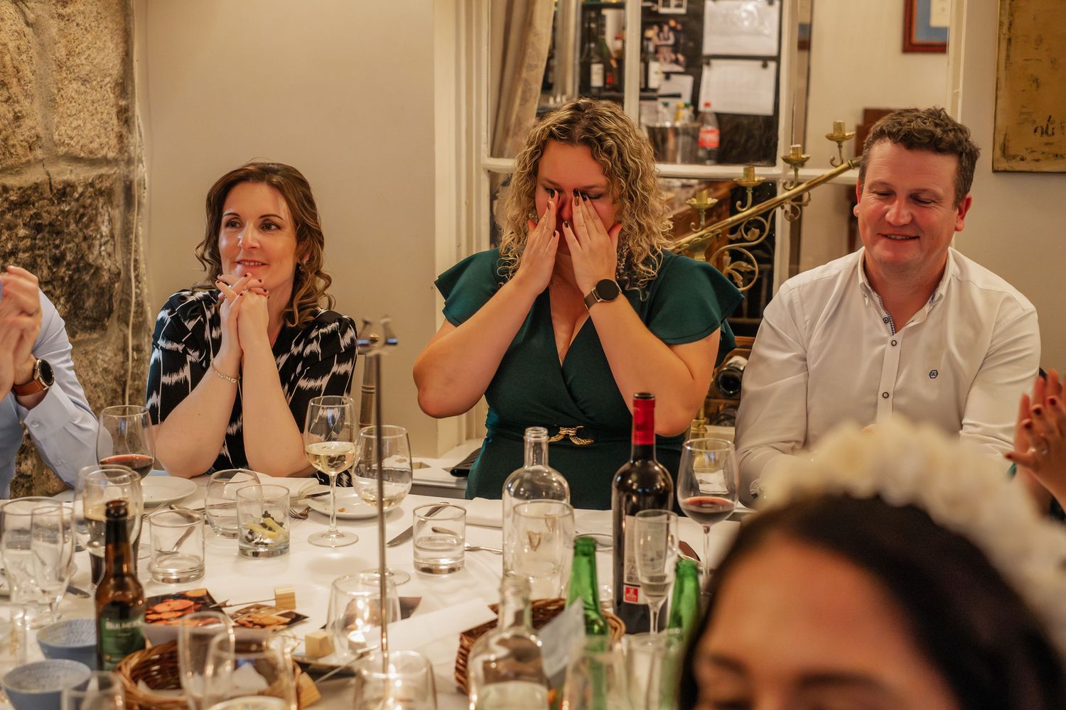 Emotional wedding guests react with hands over face during heartfelt speeches at reception dinner.