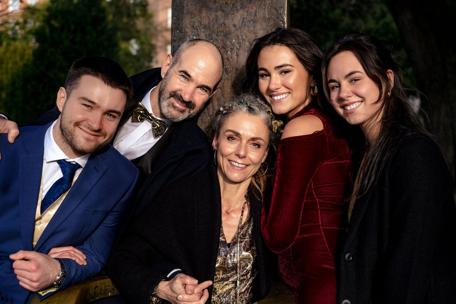 Group of five smiling people posing together outdoors at a formal event.